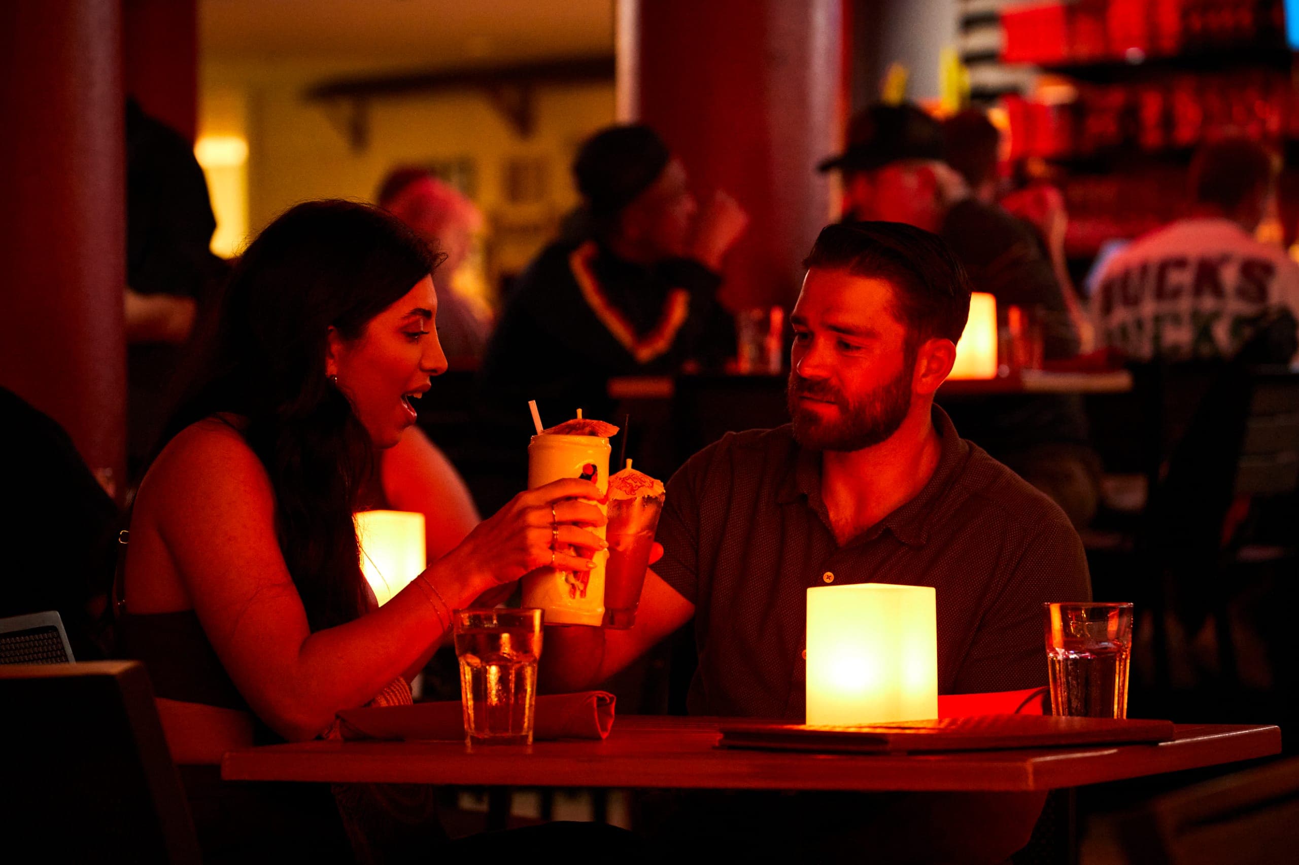 Romantic couple toasting with tropical drinks overlooking Waikiki Beach, the best restaurant in Waikiki for date night.