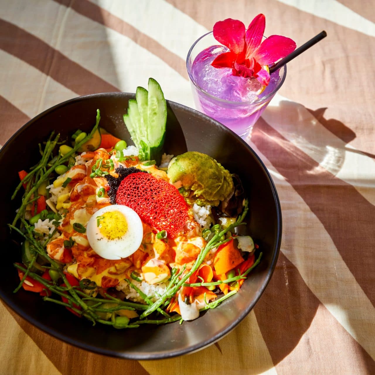 Ahi Poke dish on the menu page of Tiki's Grill & Bar's website, with a tropical drink garnished with a real orchid.